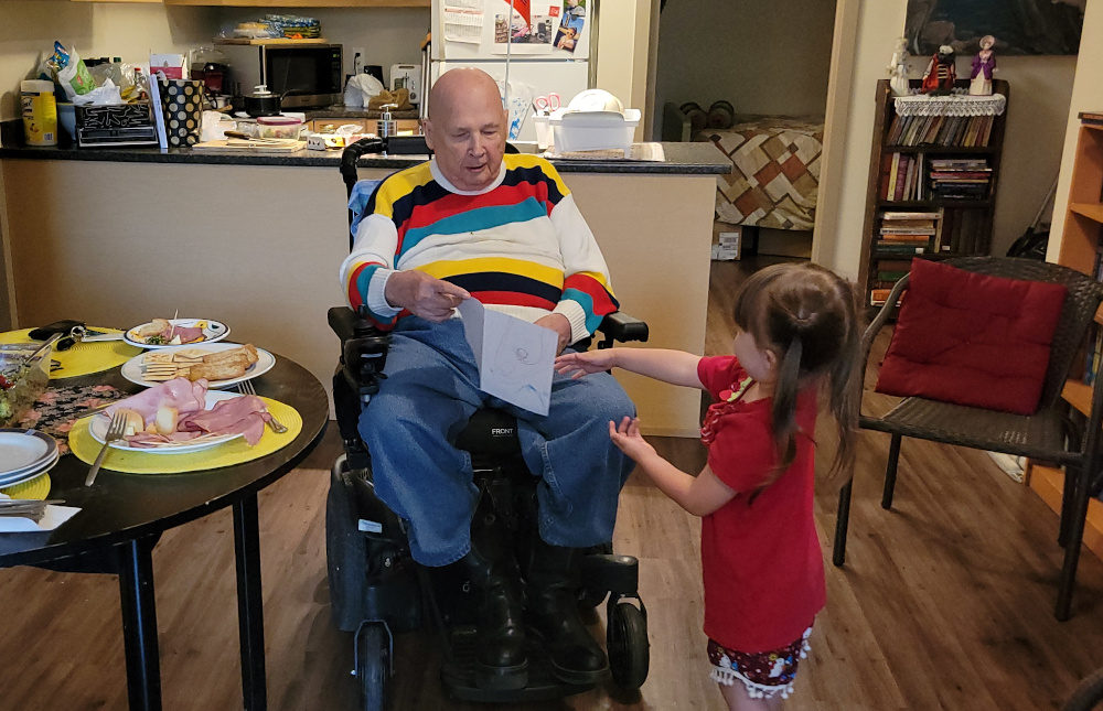Photo shows young girl giving Carl Dow a hand-made 90th birthday card.