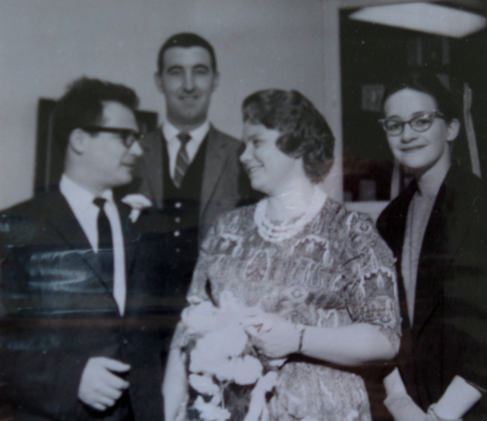 Carl Dow and Benita Dow (née Hart) look each other in the eye, while two unkown people look on.